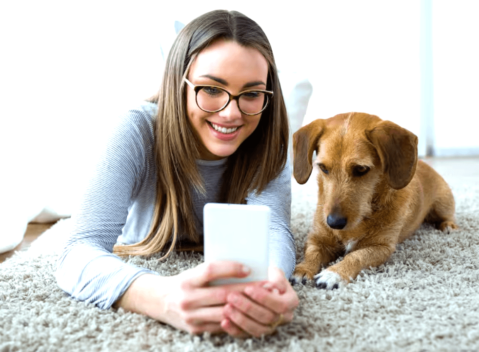 Mujer joven en su hogar realizando una teleconsulta veterinaria para su perro a través de su smartphone con TelemedicinaFull.