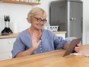 Paciente adulta mayor en consulta de nutrición y dietética online saludando a su nutricionista a través de una tablet.